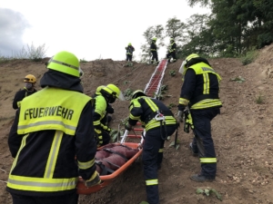 Foto zeigt, wie die Übungspuppein einer Schleifkorbtrage einen Hang hinaufgezogen wird.