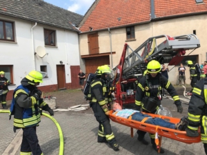 Das Bild zeigt Feuerwehrleute, die einen Verletzten mit einer Trage retten